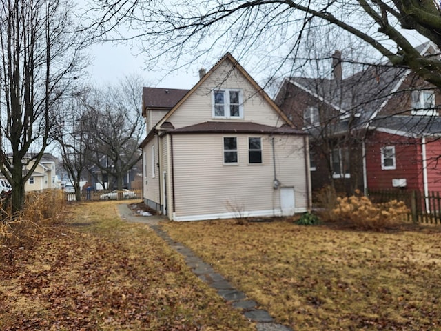 view of home's exterior with a chimney and fence