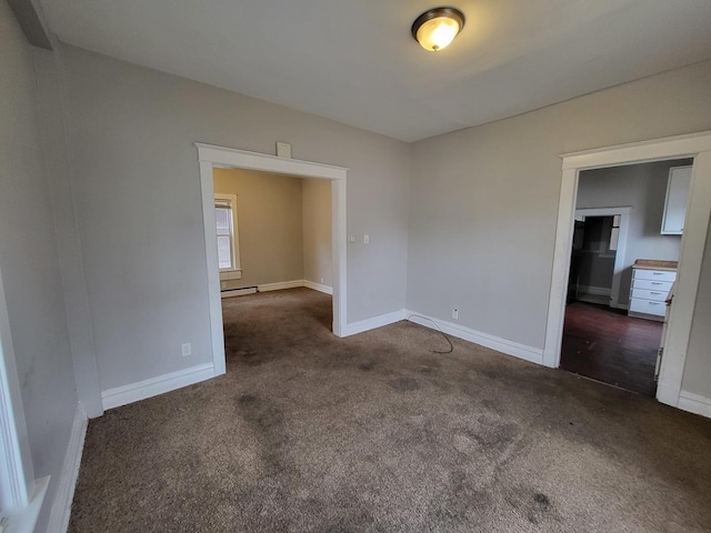 spare room with a baseboard heating unit, baseboards, and carpet floors