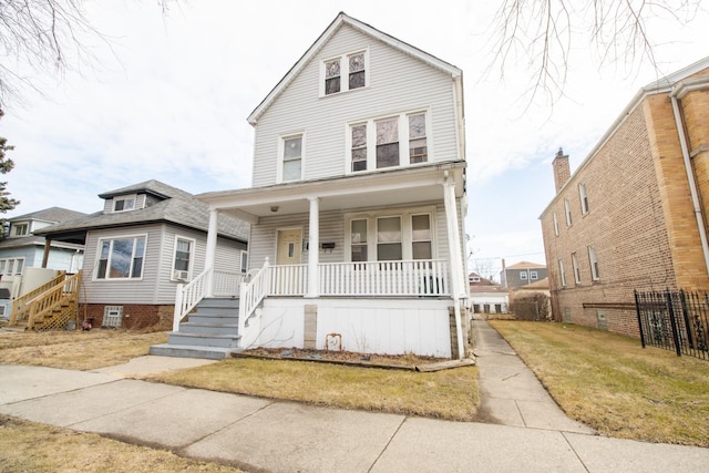 american foursquare style home with covered porch, a front yard, and fence