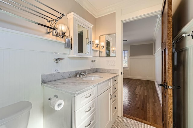 bathroom with toilet, wood finished floors, wainscoting, and ornamental molding