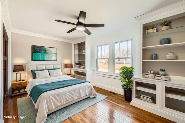 bedroom featuring visible vents, baseboards, hardwood / wood-style floors, and crown molding