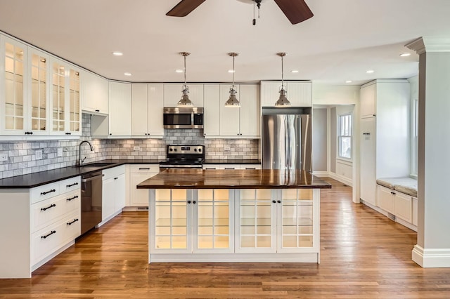 kitchen with light wood finished floors, wooden counters, a center island, stainless steel appliances, and a sink