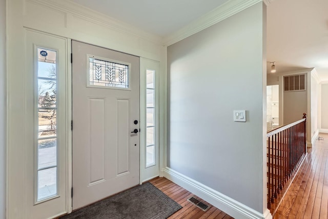 entryway with visible vents, wood-type flooring, baseboards, and crown molding