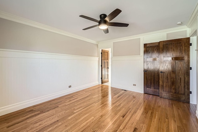 unfurnished bedroom with visible vents, wood-type flooring, a ceiling fan, and crown molding