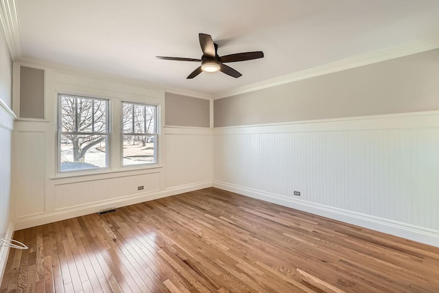 empty room featuring visible vents, crown molding, a ceiling fan, and wood-type flooring