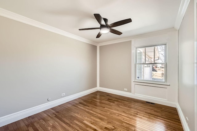 empty room with hardwood / wood-style flooring, crown molding, baseboards, and ceiling fan