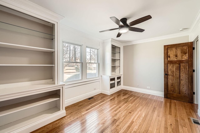 interior space featuring a ceiling fan, crown molding, baseboards, and wood-type flooring