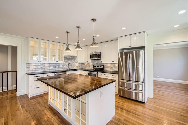 kitchen with a sink, light wood-style floors, tasteful backsplash, and appliances with stainless steel finishes