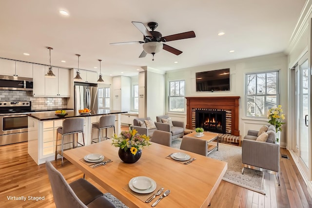 dining room featuring crown molding, a brick fireplace, recessed lighting, and light wood finished floors