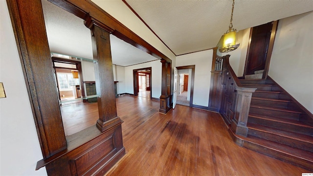 foyer with stairs, wood finished floors, ornate columns, and a textured ceiling