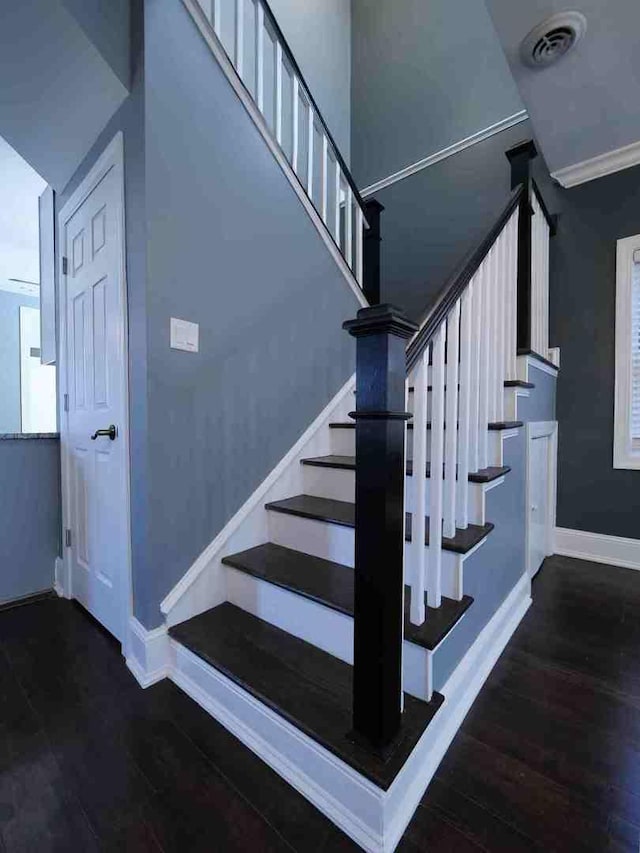 stairway with visible vents, baseboards, and wood finished floors