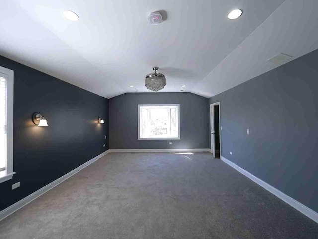 spare room with baseboards, lofted ceiling, carpet, and visible vents