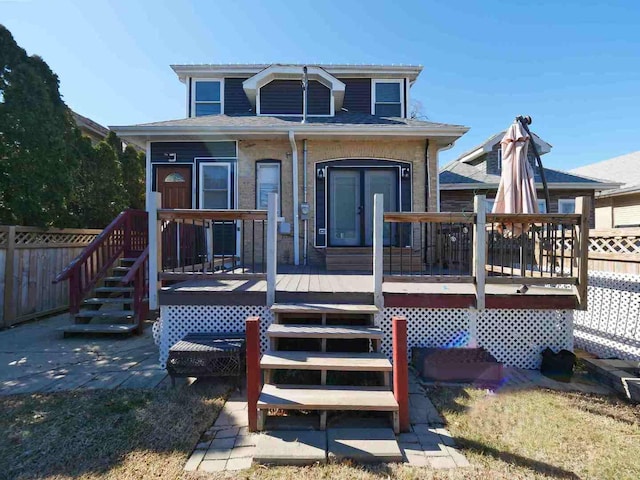 view of front of house featuring fence, roof with shingles, and a wooden deck