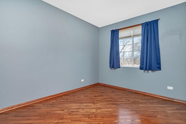 unfurnished room with visible vents, baseboards, lofted ceiling, and wood finished floors