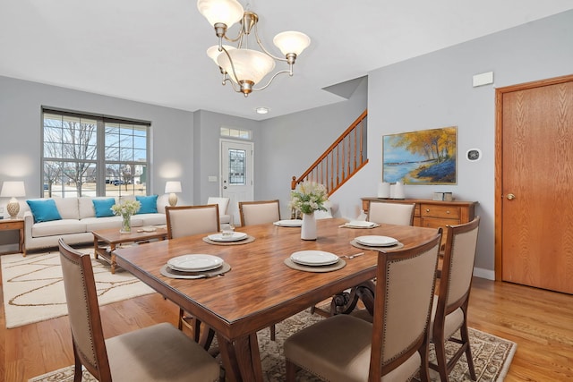 dining room with stairs, an inviting chandelier, baseboards, and light wood-type flooring