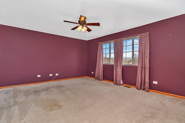 empty room with visible vents, a ceiling fan, baseboards, and carpet floors