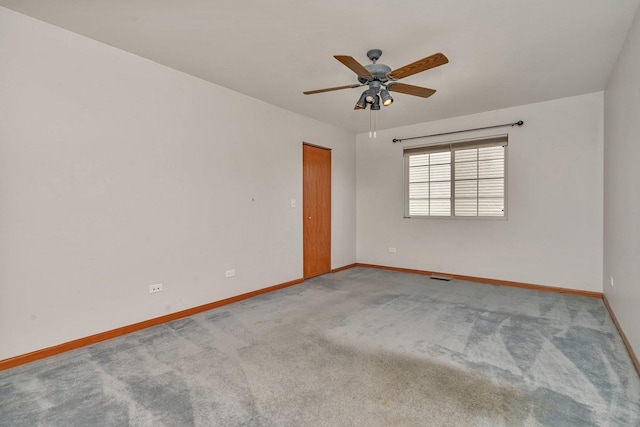 carpeted spare room featuring baseboards and ceiling fan