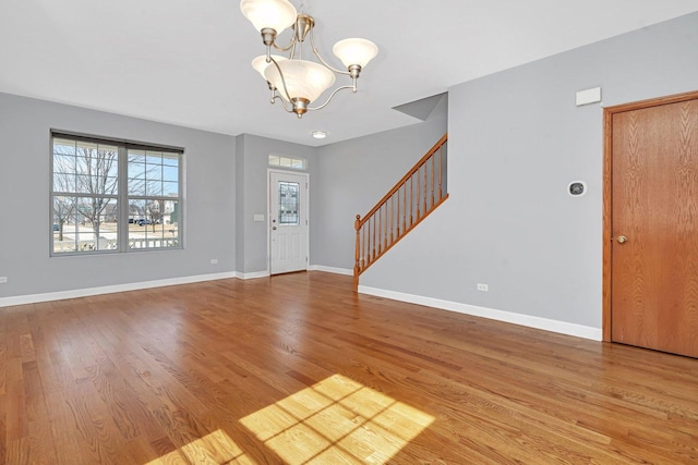 foyer entrance featuring stairway, baseboards, a notable chandelier, and wood finished floors