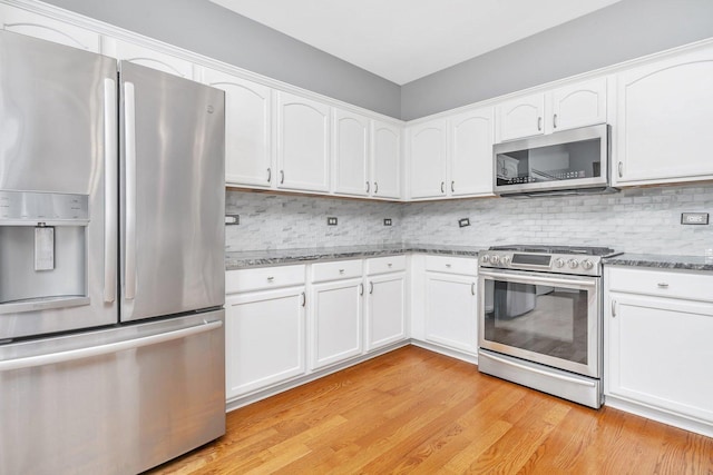 kitchen with tasteful backsplash, light wood-style flooring, appliances with stainless steel finishes, stone countertops, and white cabinetry