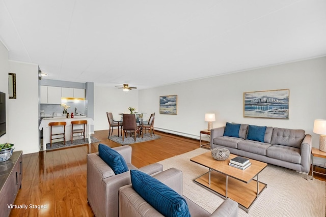 living room with a ceiling fan, baseboard heating, and light wood-type flooring
