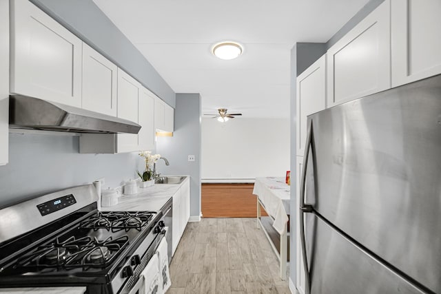 kitchen with a ceiling fan, appliances with stainless steel finishes, light wood finished floors, under cabinet range hood, and white cabinetry