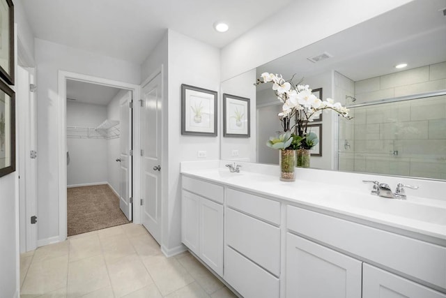 full bathroom with visible vents, a walk in closet, a stall shower, a sink, and double vanity