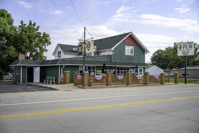 exterior space featuring a shingled roof, board and batten siding, a chimney, and fence