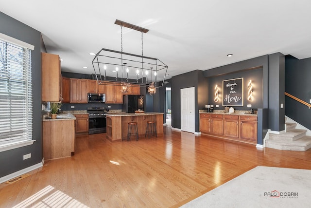 kitchen with a chandelier, brown cabinetry, stainless steel appliances, and light wood-type flooring