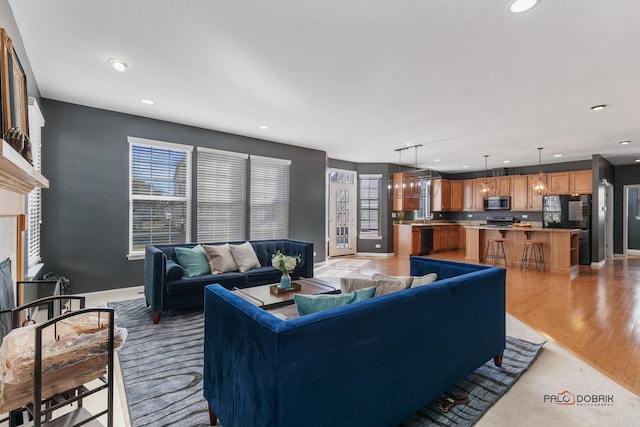 living room featuring recessed lighting, light wood-type flooring, a high end fireplace, and baseboards