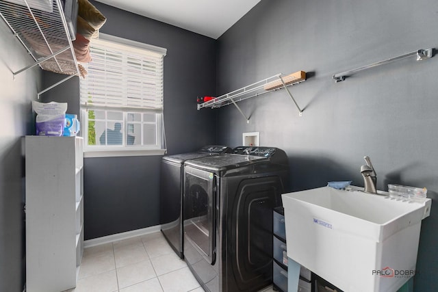 laundry area with a sink, separate washer and dryer, light tile patterned floors, baseboards, and laundry area