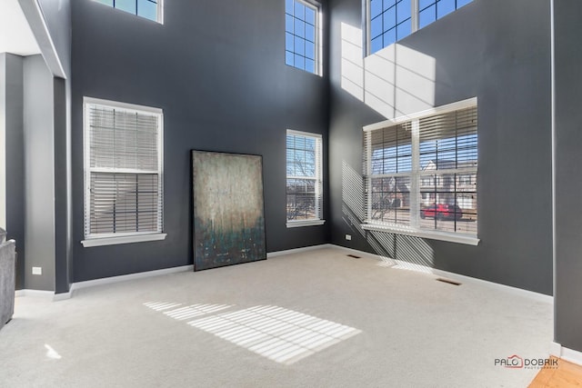 interior space with visible vents, baseboards, a high ceiling, and carpet