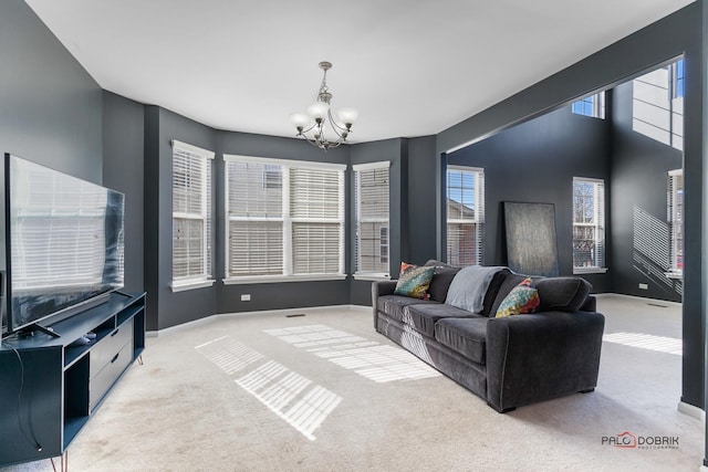 carpeted living room with a wealth of natural light, baseboards, and a notable chandelier