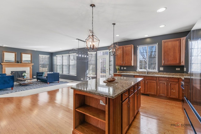 kitchen with light wood finished floors, dark stone counters, a sink, a chandelier, and a center island