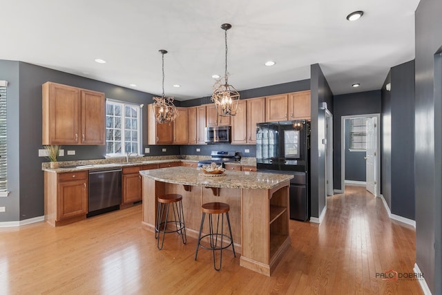 kitchen featuring a notable chandelier, light wood-style flooring, a sink, a kitchen island, and stainless steel appliances