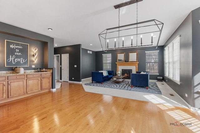 living room featuring light wood-type flooring, baseboards, and a tiled fireplace