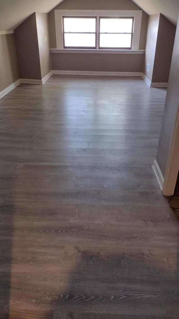 bonus room featuring a healthy amount of sunlight, baseboards, lofted ceiling, and dark wood-style flooring