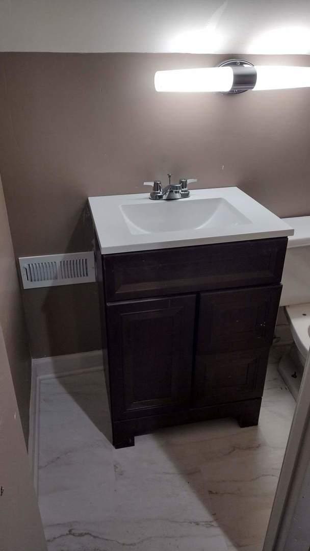 bathroom with vanity, toilet, visible vents, and marble finish floor