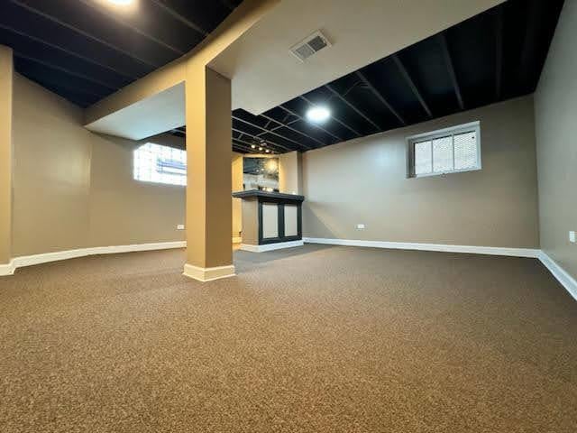 below grade area with carpet, visible vents, and baseboards