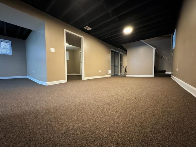 finished basement featuring stairs, visible vents, baseboards, and dark carpet