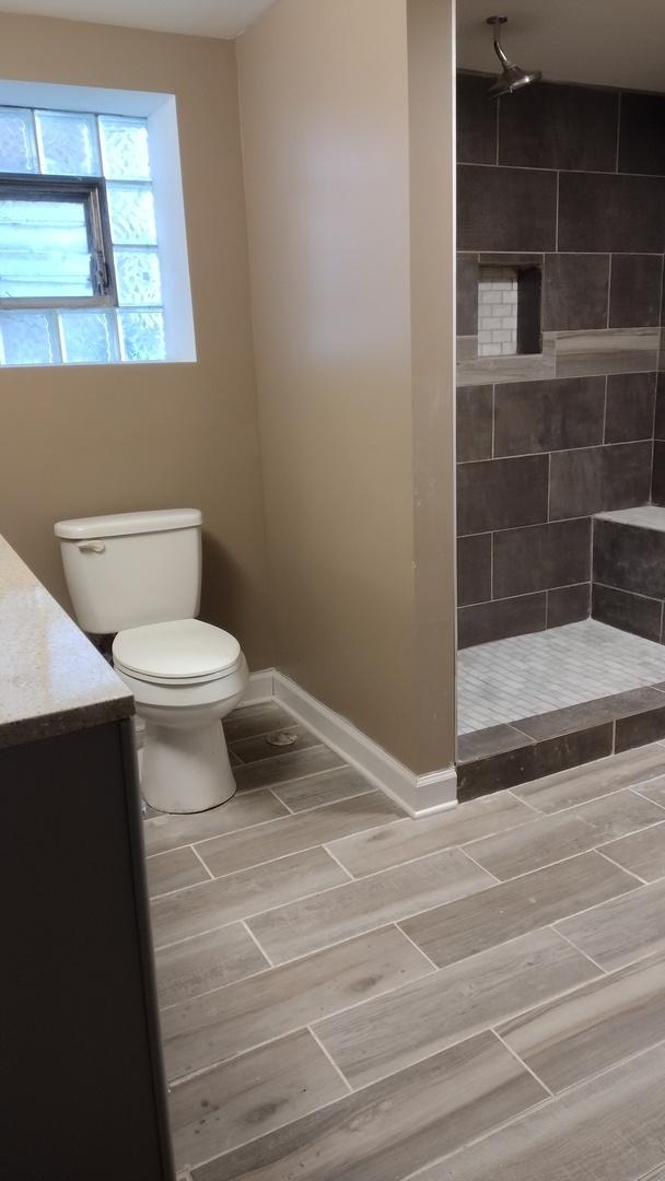 full bath featuring wood finish floors, baseboards, toilet, a tile shower, and vanity