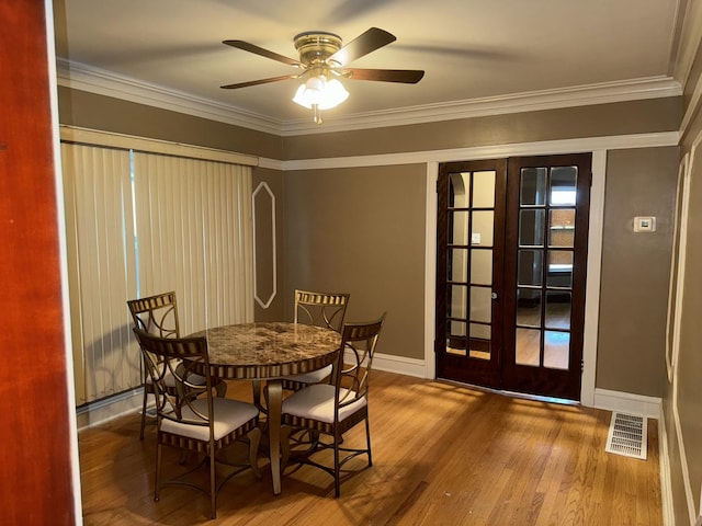 dining space with visible vents, ornamental molding, wood finished floors, french doors, and baseboards