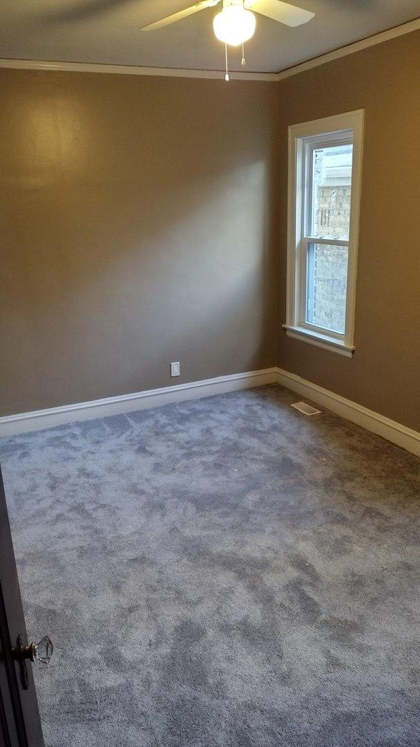 carpeted empty room featuring visible vents, a ceiling fan, baseboards, and ornamental molding