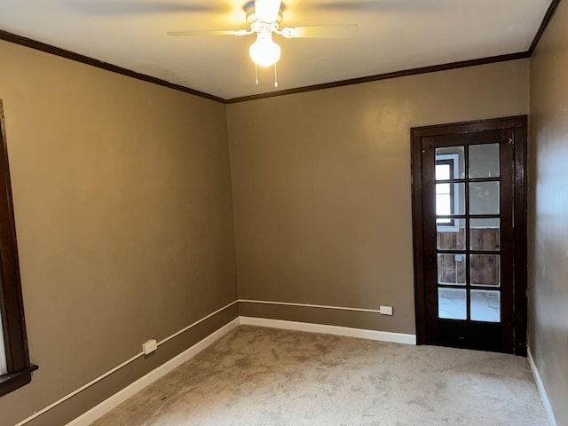 empty room with ceiling fan, carpet flooring, baseboards, and ornamental molding