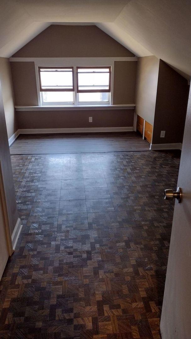 additional living space featuring baseboards and vaulted ceiling