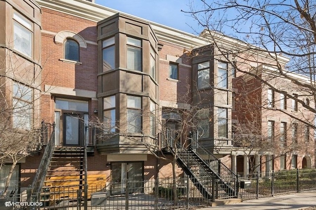 view of building exterior with stairs and fence