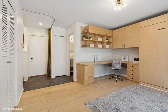 office space with baseboards, wood finished floors, and built in desk