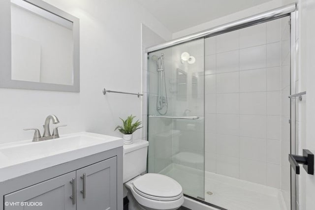 bathroom with toilet, a stall shower, and vanity