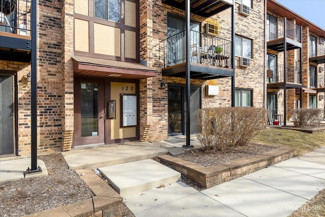 view of exterior entry with brick siding, stucco siding, and cooling unit