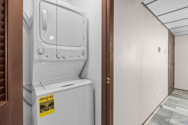 clothes washing area with stacked washer / dryer, light wood-style flooring, and laundry area