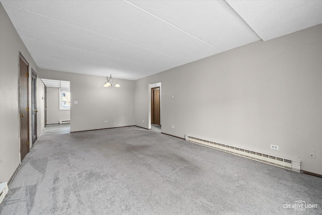 carpeted spare room with a baseboard radiator, baseboards, and an inviting chandelier